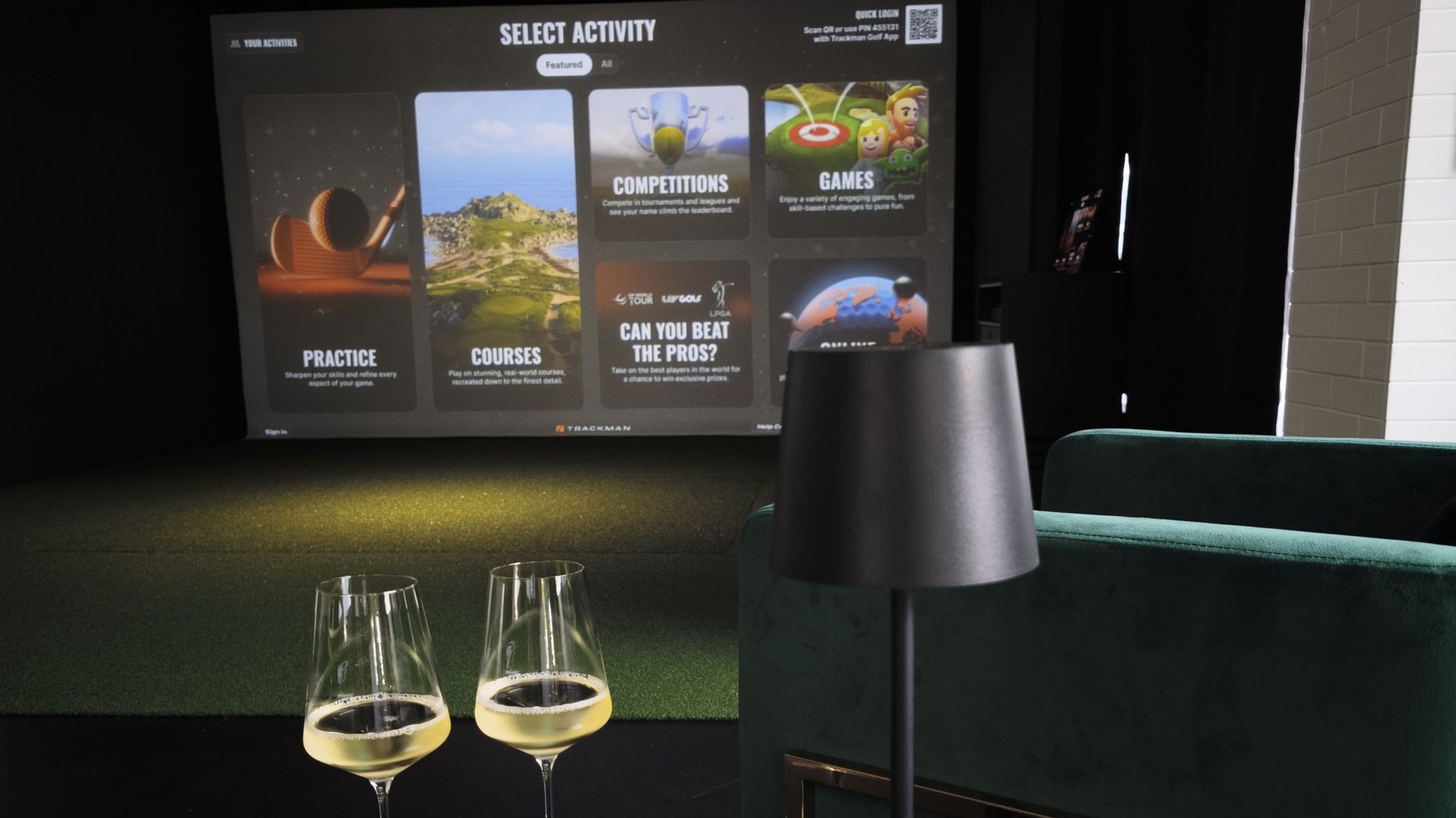 Lounge bei Hit it Hard am Abend: zwei Gläser Weißwein vor der Trackman-Leinwand
