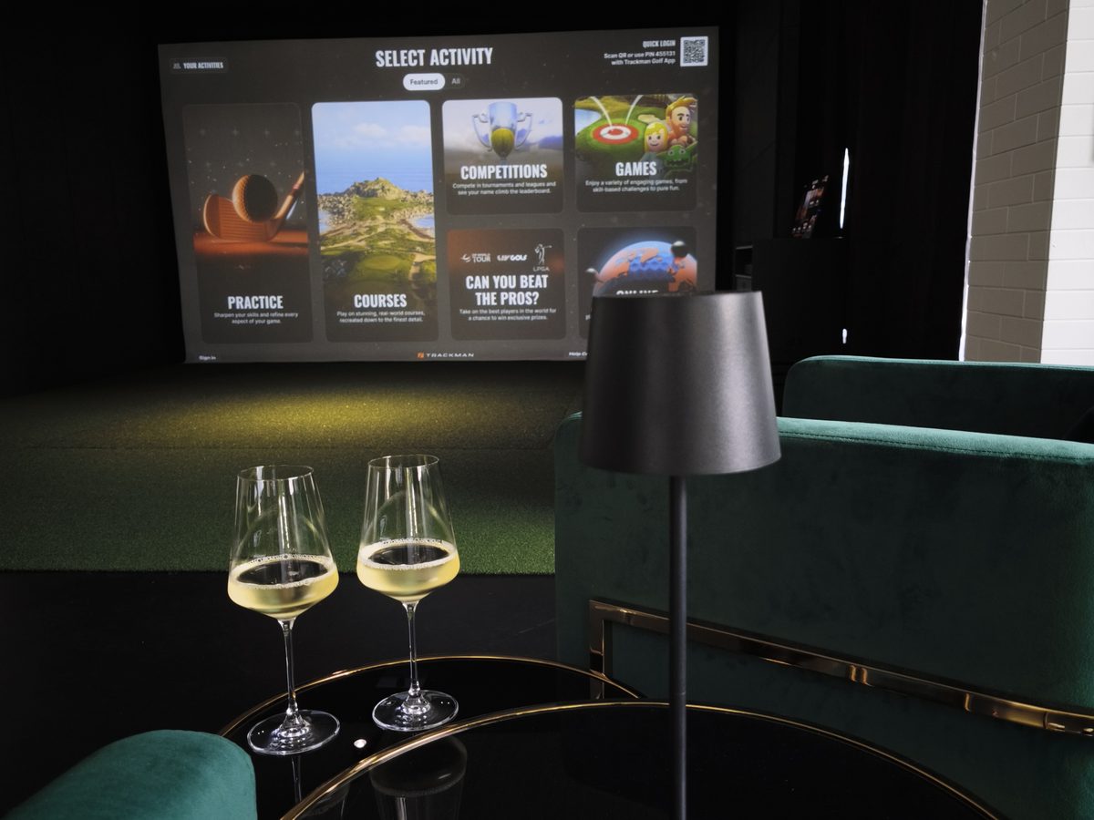 Zwei Gläser Weißwein auf dem Loungetisch vor der Trackman-Leinwand bei Hit it Hard